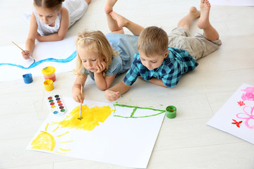 Children lying on floor in light room and painting