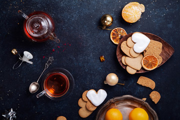 Teatime with heart-shaped ginger cookies and tangerines. Christmas background with festive decoration. Horizontal composition