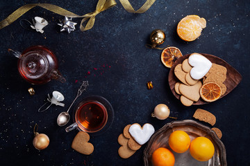 Teatime with heart-shaped ginger cookies and tangerines. Christmas background with festive decoration. Horizontal composition