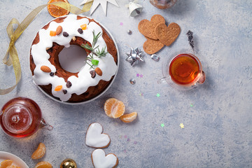 Traditional christmas cake with dried fruits soaked in rum and sugar glaze. Teatime with heart-shaped ginger cookies. Christmas background with festive decoration. Copy space.