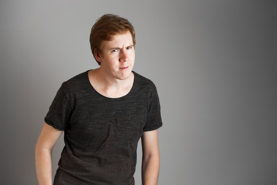 Young redheads man looking at camera surprise, dissatisfied, negative. Over grey background. Copy space.