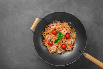 Wok with tasty pasta and shrimps on table, top view