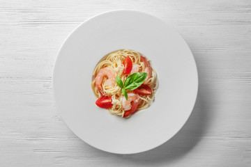 Plate of tasty pasta with shrimps on white wooden table, top view