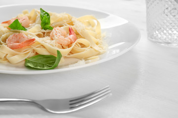 Plate of tasty pasta with shrimps on white wooden table, closeup