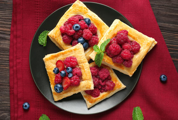 Plate with yummy berry puff pastry on wooden table