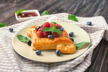 Plate with yummy berry puff pastry on table