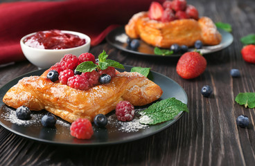 Plate with yummy berry puff pastry on wooden table