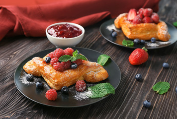 Plate with yummy berry puff pastry on wooden table