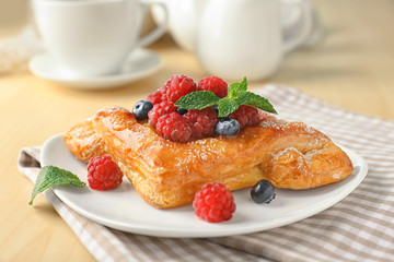 Plate with yummy berry puff pastry on table