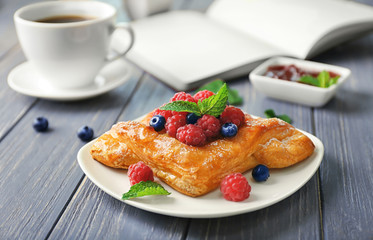 Plate with yummy berry puff pastry on wooden table