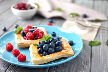 Plate with yummy berry puff pastry on wooden table