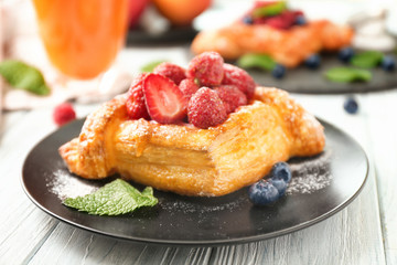 Plate with yummy berry puff pastry on wooden table