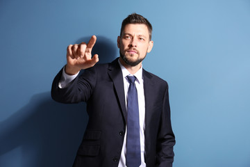 Stock exchange broker pushing button on virtual screen against color background