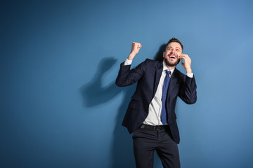 Stock exchange broker talking on phone against color background
