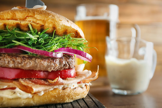 Tasty Burger With Prosciutto On Table, Close Up