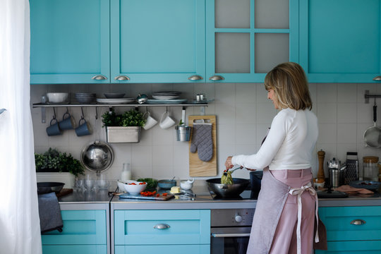 Back View Of Senior Woman Cooking Spaghetti At Home.