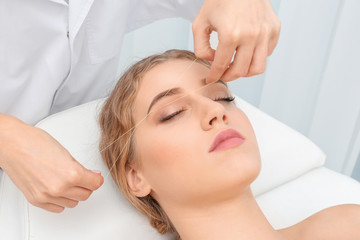 Fototapeta na wymiar Young woman having eyebrow correction procedure in beauty salon