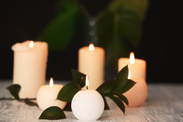Fototapeta na wymiar Burning candles on table against dark background