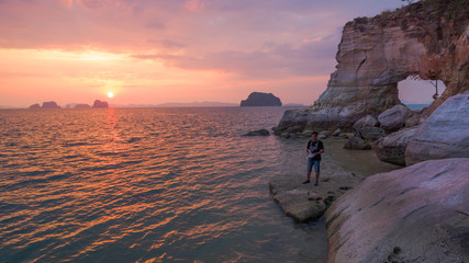 photographer take picture by drone in front of the hole in the cape  during sunset time.Leam...