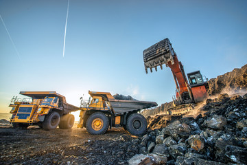 Big orange excavator in coal mine at sunny day 
