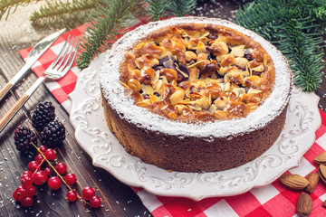 Homemade Christmas or New Year holiday berry pie with nuts on wooden table background. Concept of festive desserts
