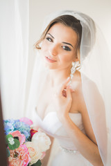 Luxury bride in white dress posing while preparing for the wedding ceremony