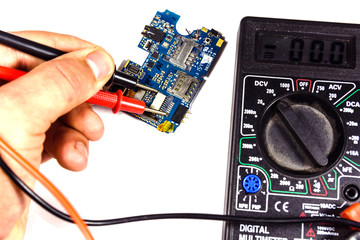 Inspecting of the electronic circuit board with multimeter. White background