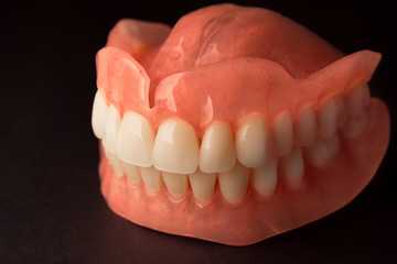 dental prostheses of the upper and lower jaws on a black background close-up