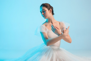 Fototapeta na wymiar Young and incredibly beautiful ballerina is dancing in a blue studio