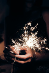 happy new year and merry christmas concept. female hand holding a burning sparkler bengal light. space for text. pyrotechnics concept,  shining fire flame