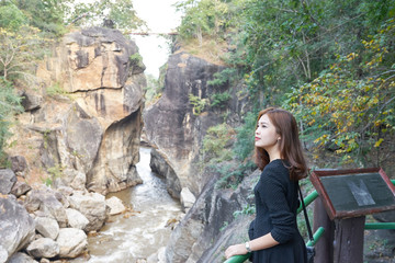 Beautiful asian woman looking something interesting at cliff near river, Op Luang national park, Chiang Mai, Thailand