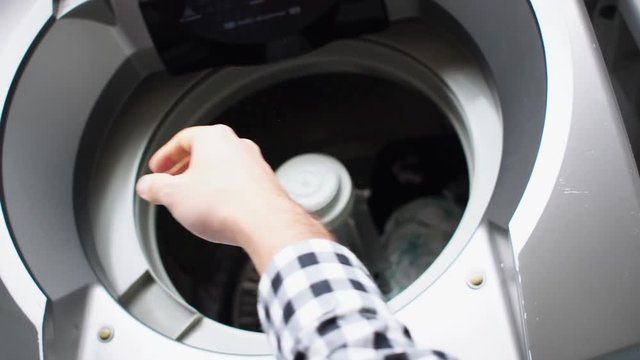 Man putting clothes in washing machine - POV