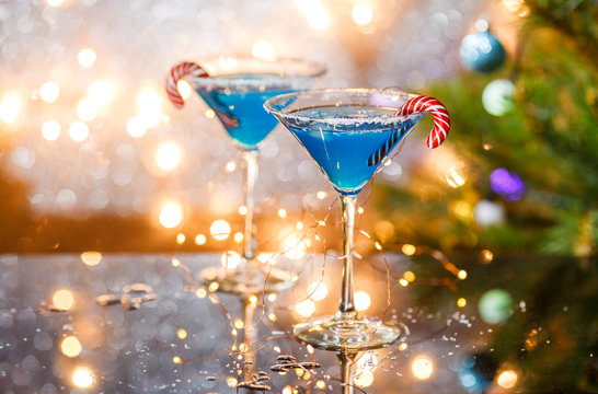 Christmas picture of two wine glasses with blue cocktail, caramel sticks and garland