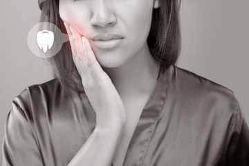 Suffering from toothache. Beautiful young woman suffering from toothache while standing against...