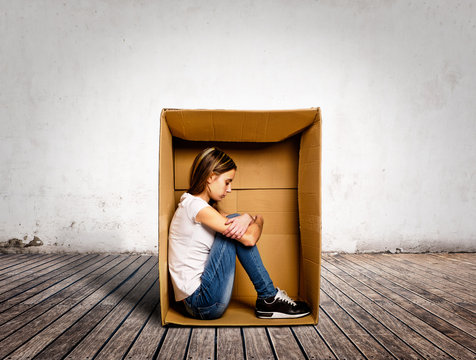 sad young woman inside a Box on a room