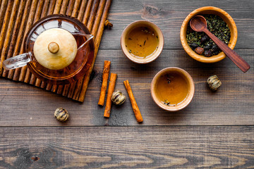 Accessories for tea ceremony. Tea pot, cups, dry tea leaves on dark wooden background top view copyspace