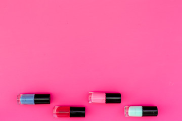 Bright decorative cosmetics. Nail polish assorted colors on pink background top view copyspace