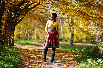 Obraz premium African american girl at yellow and red dress at golden autumn fall park.