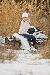 The girl is resting on the trunk of a fallen tree covered with snow 9173.
