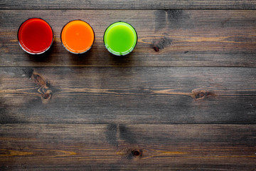 Fresh detox beverages with vegetables and fruits on dark wooden background top view copyspace