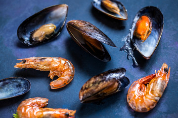 Seafood mussels in the shell and shrimp on a blue background grill