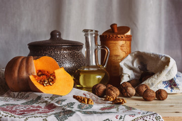  Rustic still life with pumpkin, walnuts, crockery ears of wheat and vegetable oil in a bottle