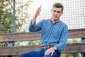 Fototapeta premium Young man sitting at the stadium watching the scene, shocked by what he saw, collision, injury of players. Emotional face. Copy space