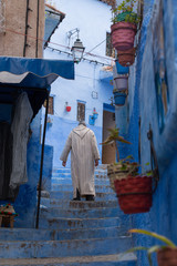 Fototapeta na wymiar Traditional moroccan courtyard in Chefchaouen blue city medina in Morocco, architectural details in Blue town Chaouen. Typical blue walls and colorful flower pots.