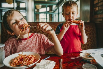children eat unhealthy food in a cafe. kids enjoy pasta and pizza