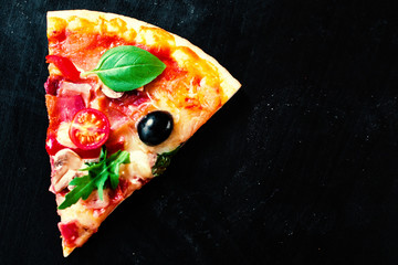 Pizza jambon, tomate et fromage sur fond sombre. Pizza chaude avec saucisse pepperoni servie dans une pizzeria ou un restaurant