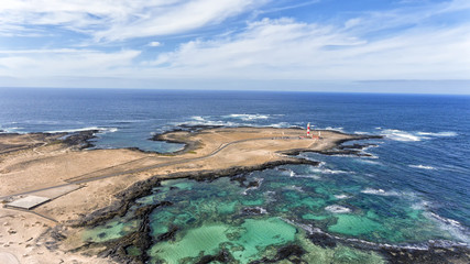 Fototapeta na wymiar Aerial view of lighthouse, turquoise lagoons, sandy beaches, rocky shore in El Cotillo, Fuerteventura, Canary Islands, Spain.