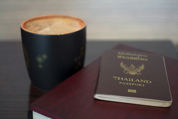Thai passport with coffee cup on wooden table