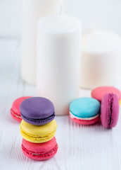 Sweet and colorful macaroon cookies against a background of candles