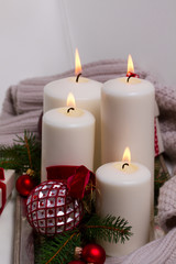 Fototapeta na wymiar Four white glowing advent candles with christmas decorations on silver tray